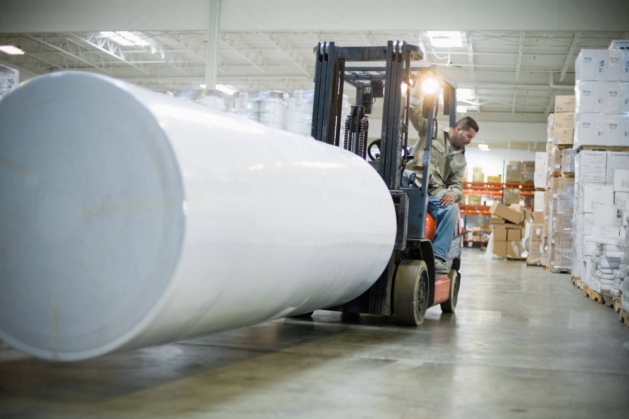 warehouse-worker-driving-forklift-with-roll-of-paper